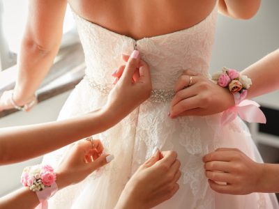 Wedding help. Hands of bridesmaids on bridal dress. Happy marriage and bride at wedding day concept