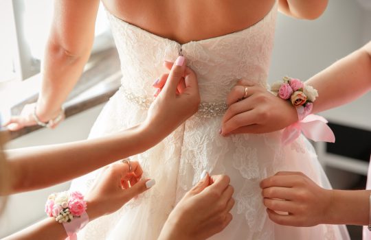Wedding help. Hands of bridesmaids on bridal dress. Happy marriage and bride at wedding day concept