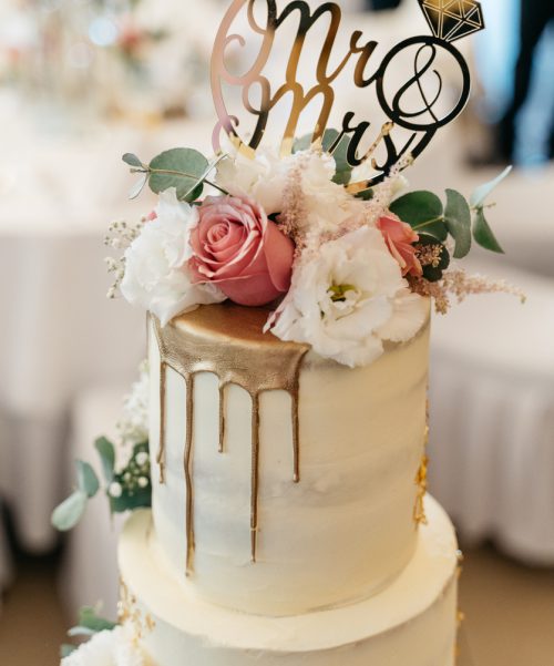half naked wedding cake with mr. and mrs. signs, flowers and gold decoration